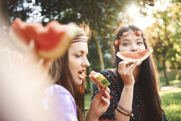 Young boho women making smiley face with melon slice at festival - ISF05839