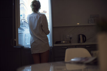 Rear view of woman wearing shirt looking into fridge - ISF05842