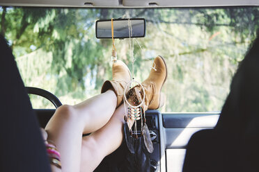 Young woman in ankle boots with feet up in recreational van - ISF05844