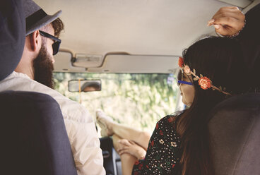 Over shoulder view of young boho couple with feet up in recreational van - ISF05845