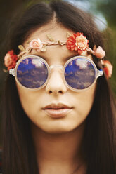Porträt einer jungen Hippie-Frau mit geblümtem Stirnband und Sonnenbrille auf einem Festival - ISF05850