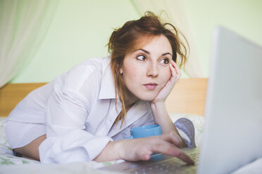 Young woman kneeling on bed using laptop - ISF05911