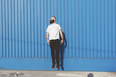Bearded man in front of blue wall jumping in mid air - ISF05923