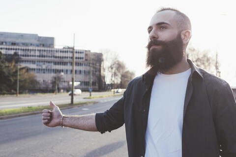 Bärtiger Mann beim Trampen, lizenzfreies Stockfoto