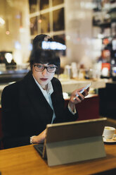 Geschäftsfrau mit Mobiltelefon und digitalem Tablet in einem Café - ISF05978