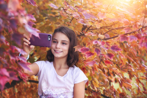 Junges Mädchen in ländlicher Umgebung, das mit seinem Smartphone ein Selfie macht, lizenzfreies Stockfoto