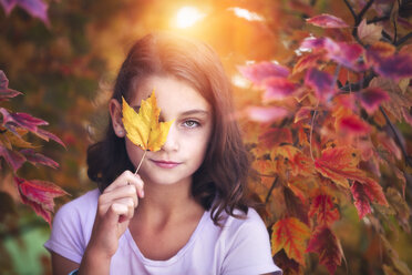 Portrait of young girl in rural setting, holding leaf in front of eye - ISF06018