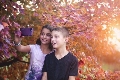 Junge und Mädchen in ländlicher Umgebung, die ein Selfie mit ihrem Smartphone machen, lizenzfreies Stockfoto