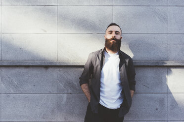 Man with a beard and a radiant skin tone stands in a studio, wearing a  perfect smile on his face. Happy young man embracing his beauty and  masculine looks, expressing confidence and