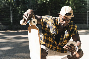 Cooler junger Mann im Skatepark, der sein Smartphone benutzt - UUF13836