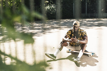 Cooler junger Mann im Skatepark, der sein Smartphone benutzt - UUF13839