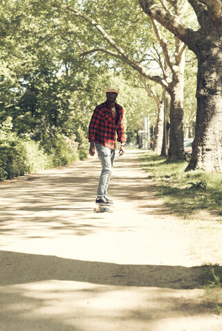 Cooler junger Mann auf dem Skateboard im Park, lizenzfreies Stockfoto