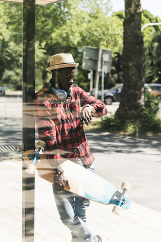Cooler junger Mann mit Kopfhörern, der an der Bushaltestelle wartet, lizenzfreies Stockfoto