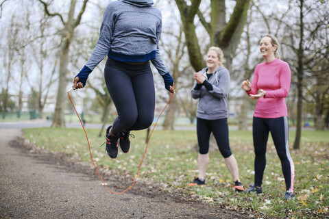 Cropped view of young woman and friends training with skipping rope in park stock photo