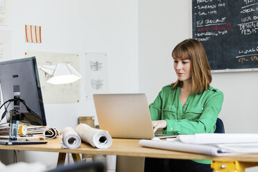 Frau sitzt am Schreibtisch im Büro und arbeitet am Laptop - ISF06125