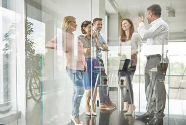 Blick durch Glas auf Kollegen, die sich im Büro unterhalten - ISF06150