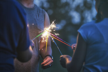 Cropped shot of women and girl igniting sparklers together at dusk on independence day, USA - ISF06197