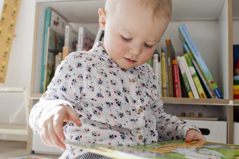 Weibliches Kleinkind liest Buch im Spielzimmer - CUF13286