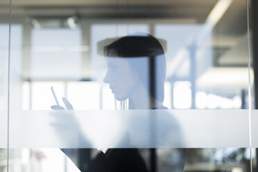 Side view through window of young woman holding digital tablet - CUF13362