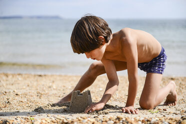 Boy making sandcastle on beach - ISF06235