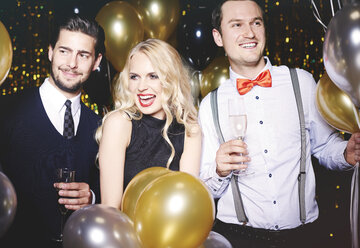 Portrait of three people at party, surrounded by balloons, holding champagne glasses - ISF06252