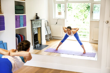 Spiegelbild einer Frau, die sich in einer Yoga-Position nach vorne beugt - ISF06281