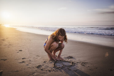 Girl drawing heart in sand on beach - ISF06302