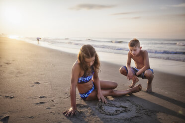 Girl drawing heart in sand on beach - ISF06303