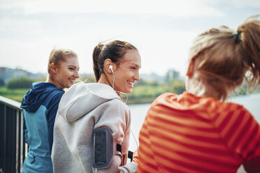 Three female runners chatting on city footbridge - CUF13427