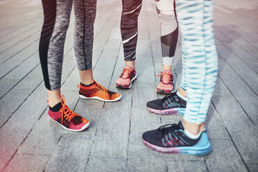 Legs of three female runners standing on wooden pier - CUF13430