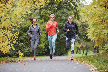 Three female runners running along park path - CUF13434