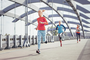 Drei Läuferinnen laufen über die Fußgängerbrücke der Stadt - CUF13437