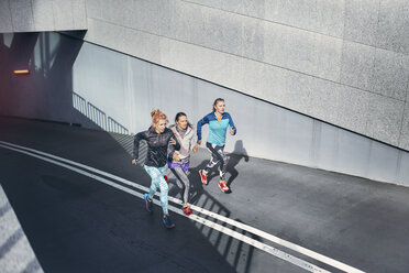 Three female runners racing up city underpass - CUF13443