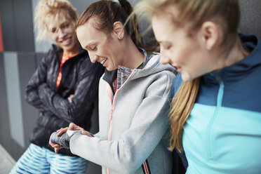 Three female runners checking time in city underpass - CUF13445