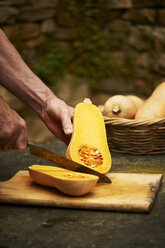 Senior mans hands chopping butternut squash with knife on cutting board - CUF13446