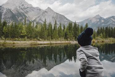 Junge mit Blick auf die Spiegelung von Bergen und Bäumen im See, Canmore, Kanada, Nordamerika - ISF06328