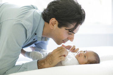 Father leaning on bed, looking at newborn baby boy - ISF06397