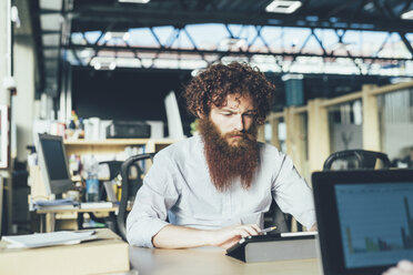 Junger männlicher Hipster mit digitalem Tablet am Schreibtisch - CUF13583