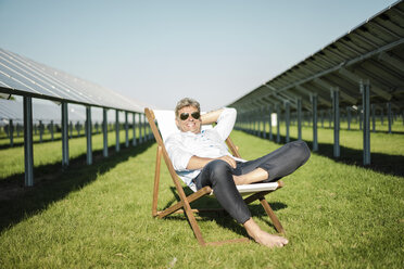 Älterer Mann sitzt im Liegestuhl, Solaranlage - MOEF01120