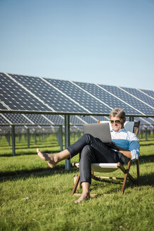 Älterer Mann im Liegestuhl sitzend, mit Laptop, Solaranlage - MOEF01122