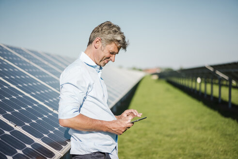 Businessman using tablet at solar park - MOEF01125