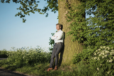 Businessman leaning on tree - MOEF01130