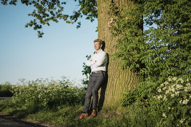 Geschäftsmann lehnt an Baum - MOEF01130