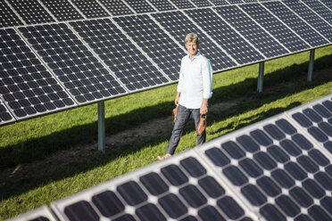 Älterer Mann geht barfuß auf einer Wiese in einer Solaranlage - MOEF01139