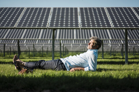 Älterer Mann liegt barfuß auf einer Wiese, Solaranlage, lizenzfreies Stockfoto