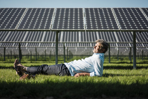 Älterer Mann liegt barfuß auf einer Wiese, Solaranlage - MOEF01146