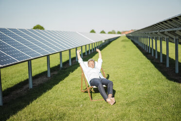 Mature man sitting in sun lounger, solar plant - MOEF01151