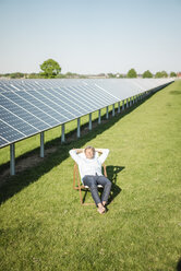 Mature man sitting in sun lounger, solar plant - MOEF01152
