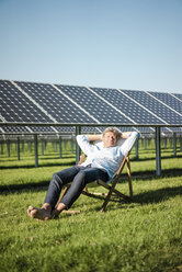 Älterer Mann sitzt im Liegestuhl, Solaranlage - MOEF01153