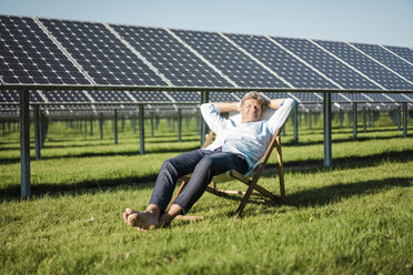 Mature man sitting in sun lounger, solar plant - MOEF01154
